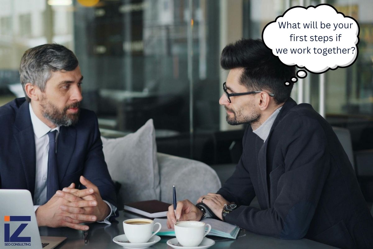 Business owner asking an SEO consultant 'What will be your first steps if we work together?' during a strategy meeting